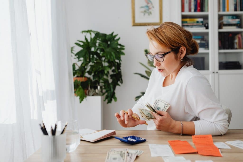 Woman Sitting at Desk Counting Money