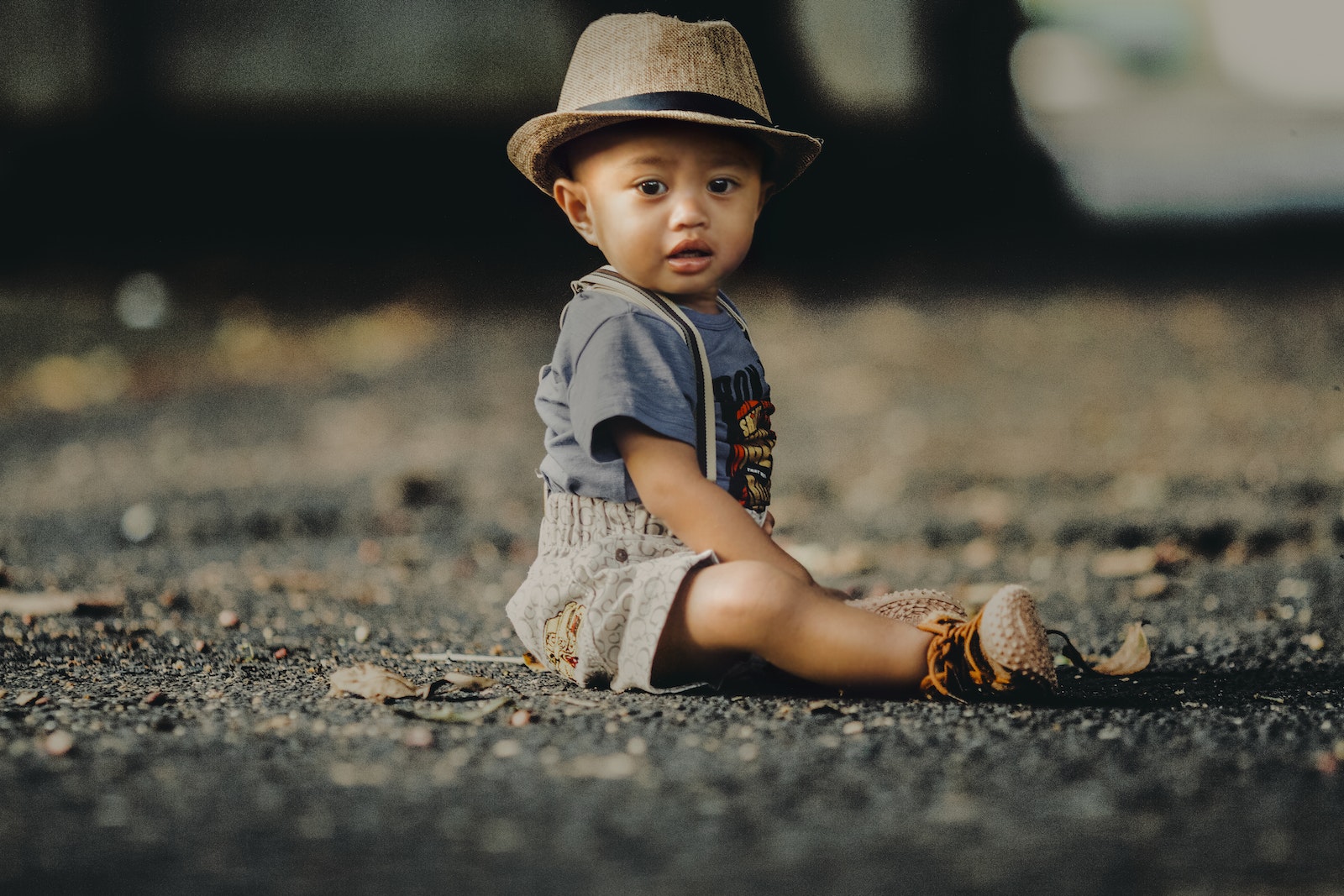 Child In Grey Shorts Sitting On Road