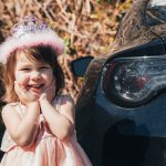 girl in pink dress sitting on black car